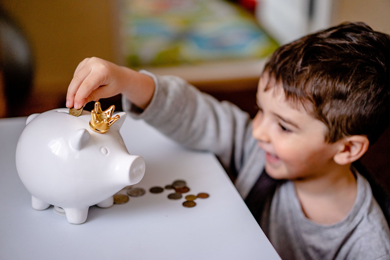 Smiling child saving coins in a piggy bank